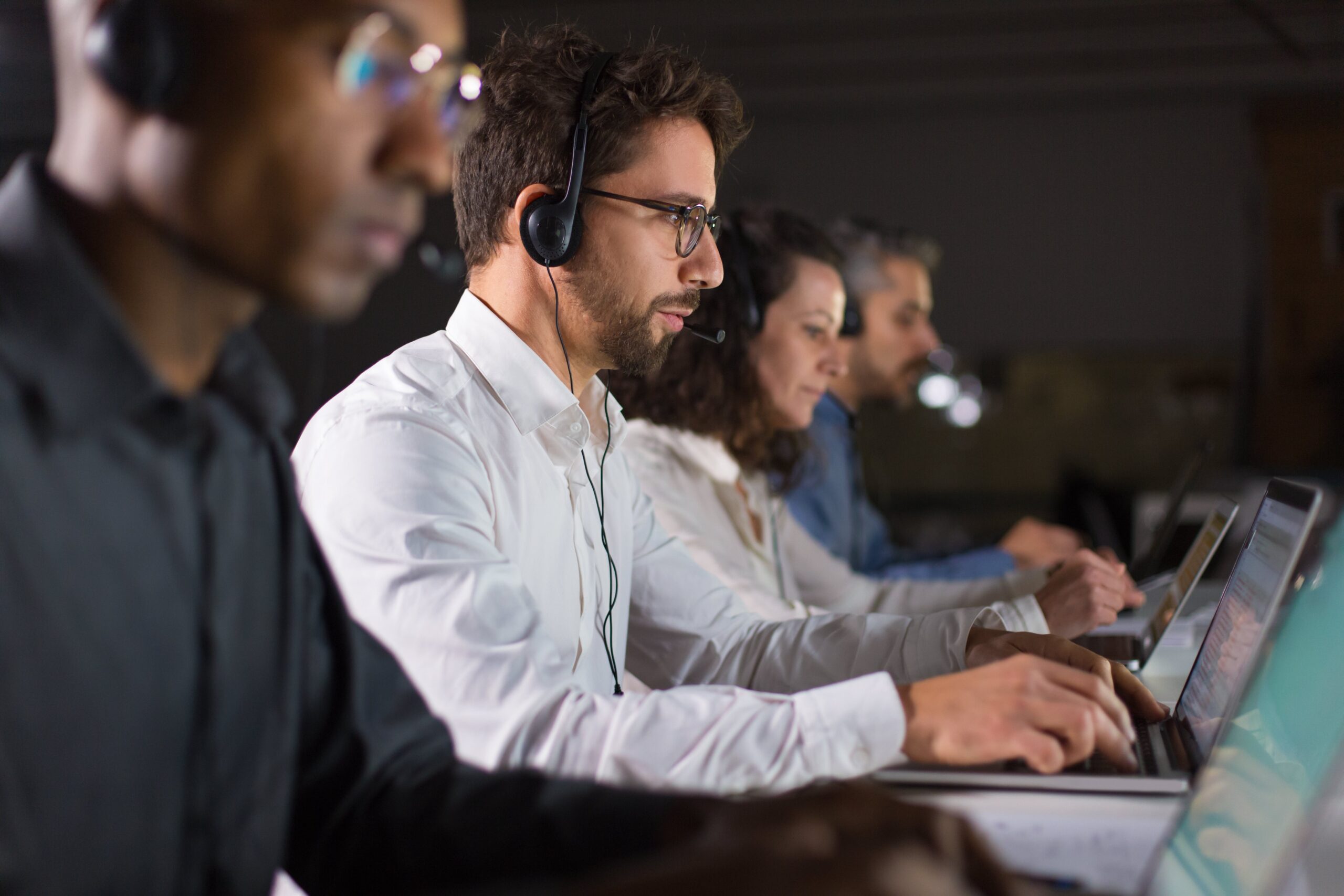 Side view of confident call center operator talking with client